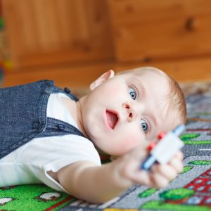 Lovely baby boy playing with toys at home. Cute funny child having fun with playing. Kid development concept.